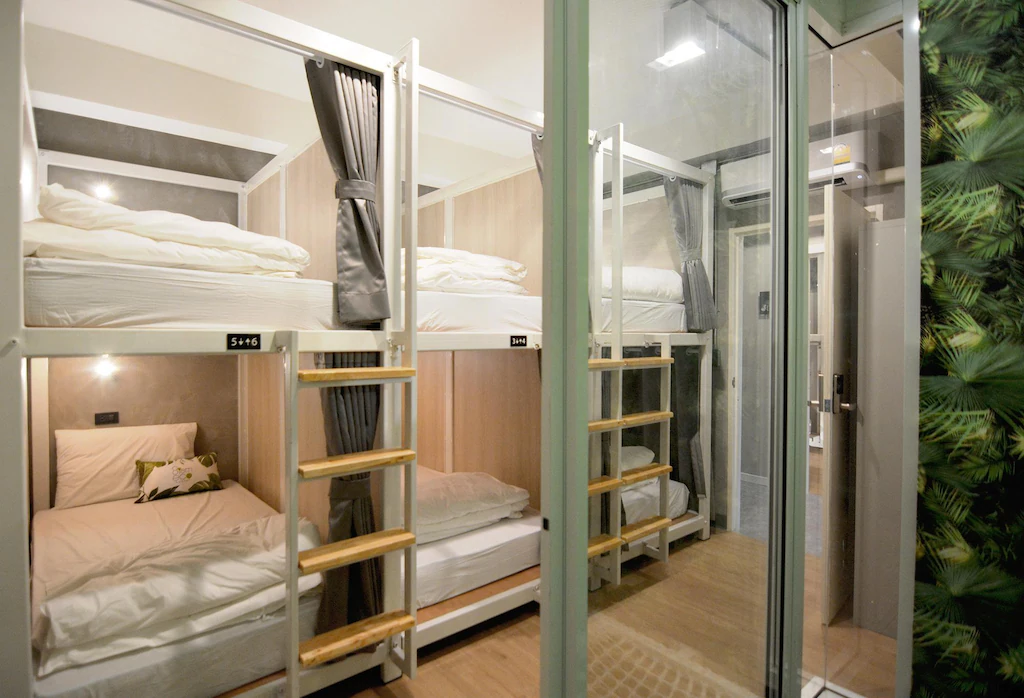 Dorm with grey capsule curtains and wooden ladders