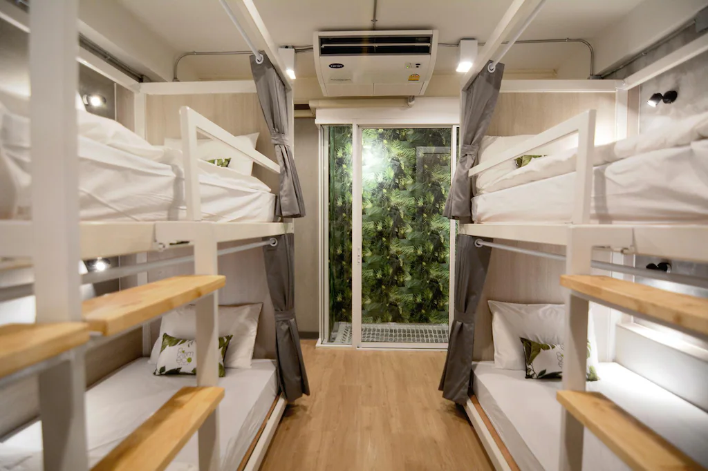 Ladies dorm with white bunks, wooden shelves and a leaf-print door