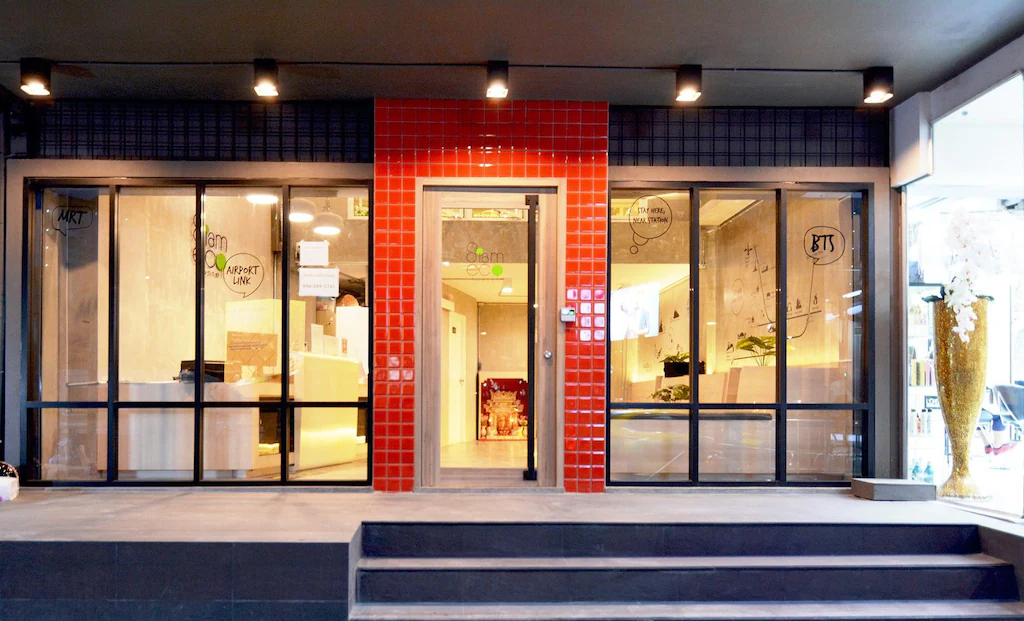 The glossy red-tiled entrance of Siam Eco Hostel at street level