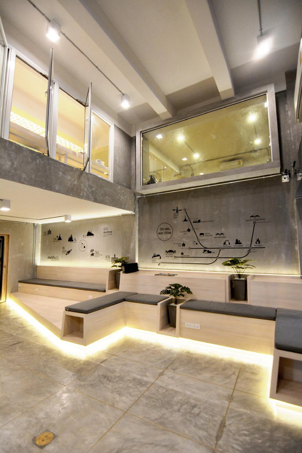 Double-height lobby atrium with wooden bench seating and the train mural