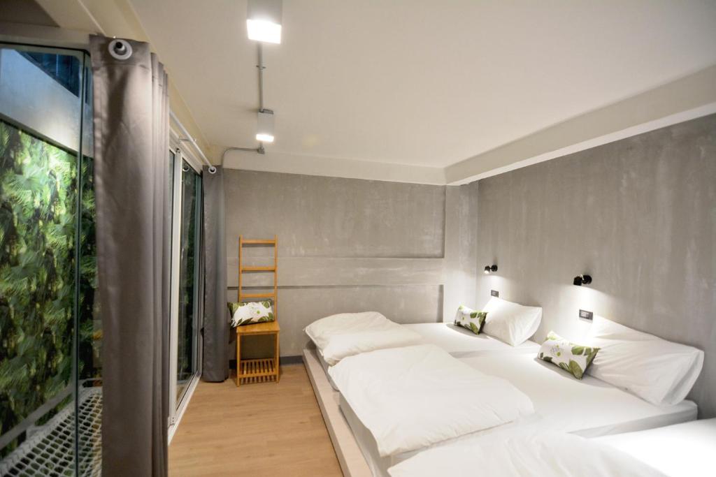 Private room with low platform beds, grey concrete walls and a garden window